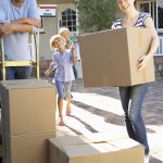 family moving boxes out of moving truck - new house